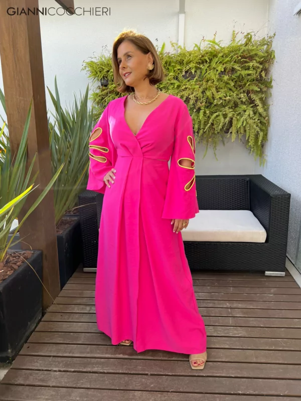 Vestido rosa choque com decote profundo e manga comprida e aberta com recortes em detalhes amarelo neon. Saia na altura do tornozelo.